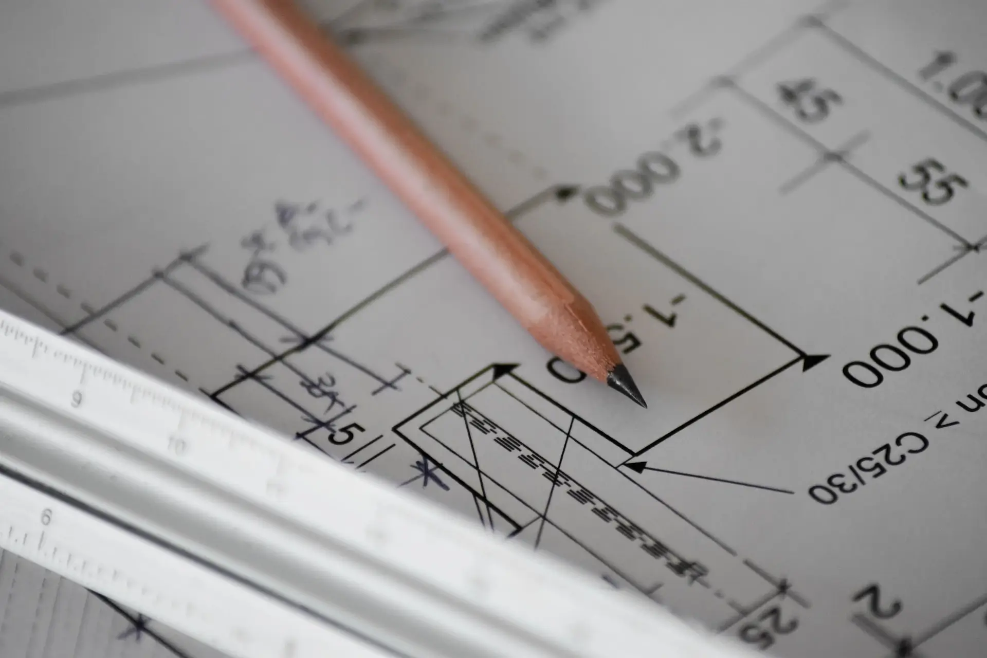 Plan architektoniczny zawierający szczegółowy rysunek ołówkiem z pomiarami i notatkami projektowymi, wraz z metalową linijką do skalowania.